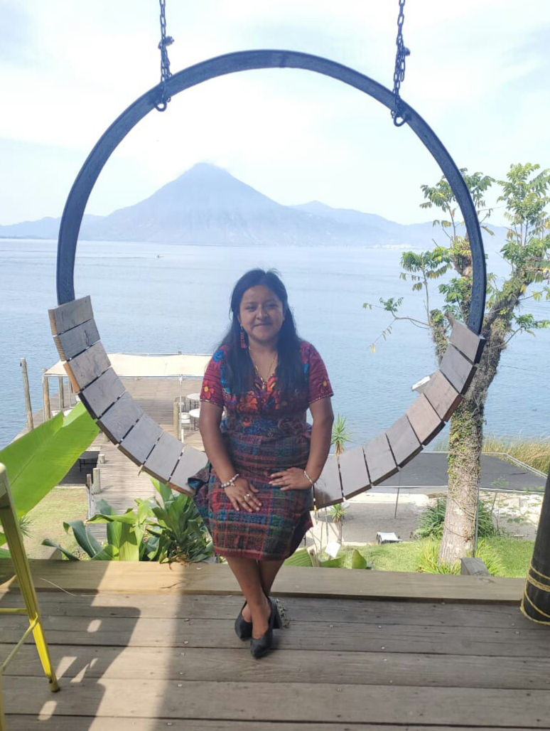 A young woman sits in front of Lake Atitlán