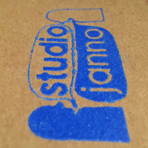 Un logo bleu texturé sur fond carton brut avec deux petits personnages qui parlent. Ont lit dans les bulles "studio janno".