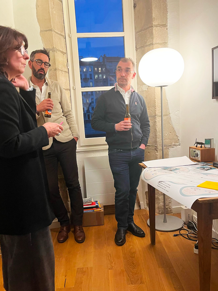 Sophie, Frédéric et Lois regardent les outils en discutant autour d'une bière.