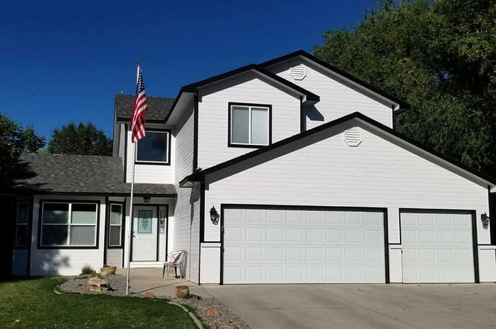 White modern farmhouse exterior painting with black trim and garage doors in Grand Junction by Prime Painting Experts