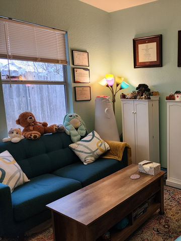 Welcoming therapy office: calming teal couch, toys, and soft lighting