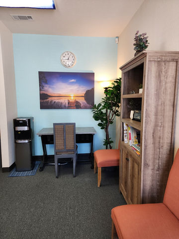 Calm waiting area with desk, books, and calming beach print