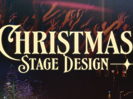 Christmas church stage with a simple manger and trees in front of an LED video wall showing a warm nativity sky.