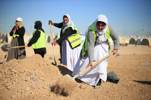 Femmes yézidies en gilets de sécurité creusant la terre.