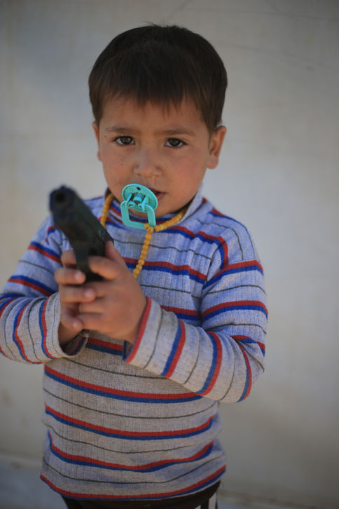 Enfant yézidi avec une tétine tenant une arme factice.