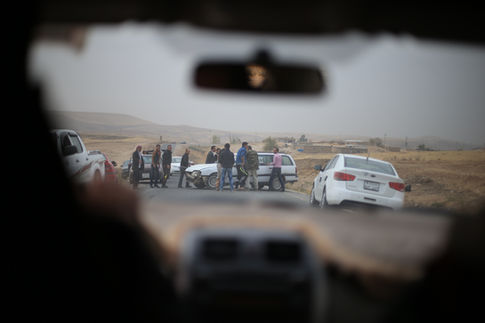 Groupe de Yézidis rassemblés autour d'une voiture sur une route.