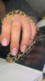 Gepflegte Hand mit rosa Nägeln hält eine goldene Kette.