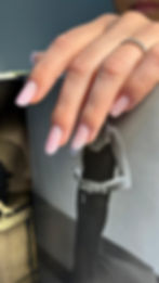 Gepflegte Hand mit rosa Maniküre und Ring auf einem Magazin.
