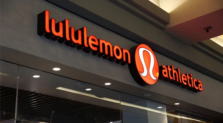 Illuminated lululemon athletica storefront sign in orange and black above a glass shopfront.
