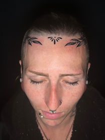 Leaf tattoos on either side of forehead along with a design located the widow’s peak