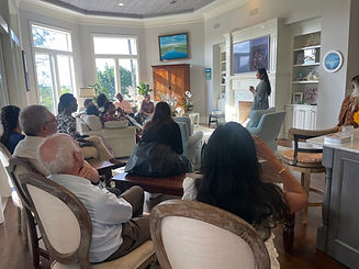 Teen girl standing by fireplace speaking to living room full of people