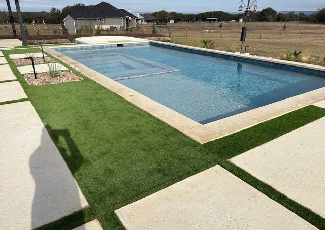 Native Hill Country plants, boulder accents, and river rock beds surrounding outdoor kitchen pavilion and pool in Boerne 