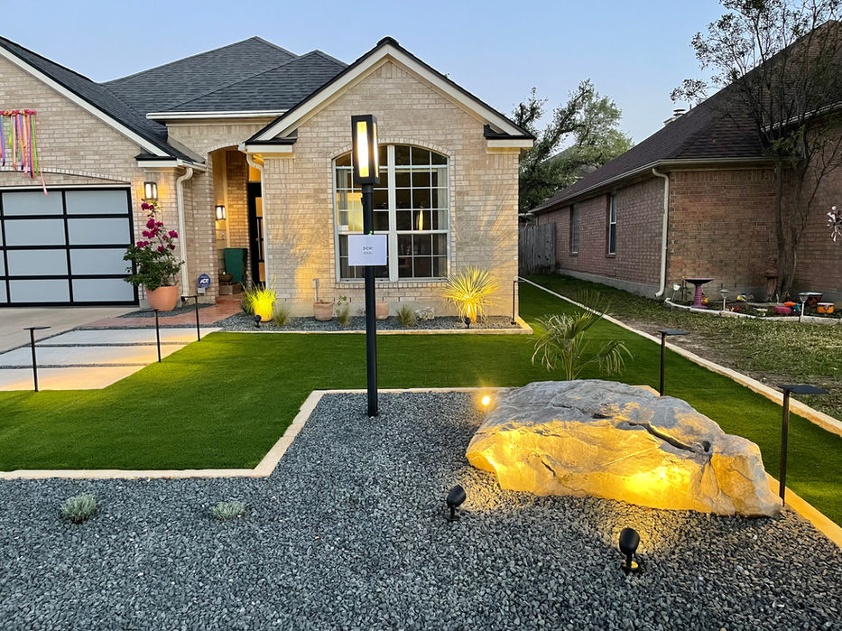 San Antonio front yard with turf and boulder lit at night