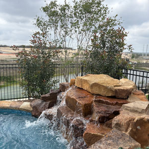 Backyard landscape design with pool, retaining wall, and synthetic turf in Regency at Esperanza Boerne TX