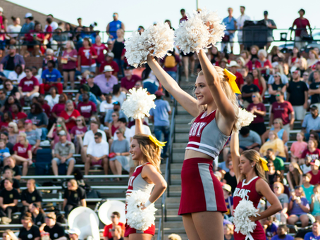 Cheerleaders and bleachers full of people.