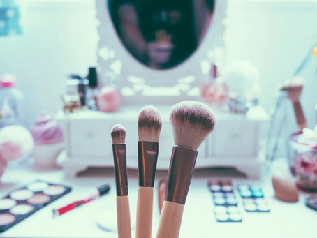 Makeup brushes in front of a vanity mirror.