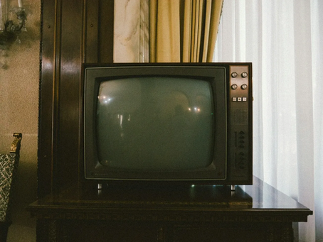 A vintage TV on top of a wooden dresser.