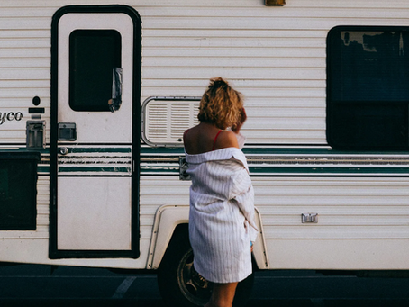 A woman standing in front of a camper.