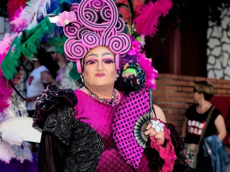 A drag queen holding a fan.