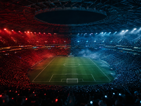 Packed soccer stadium glowing red on the left and blue on the right, with a lit green field at center and a dramatic night mood
