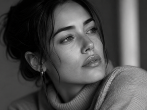 Black and white portrait of a woman gazing thoughtfully to the side, wearing a cozy sweater. The mood is introspective and serene.