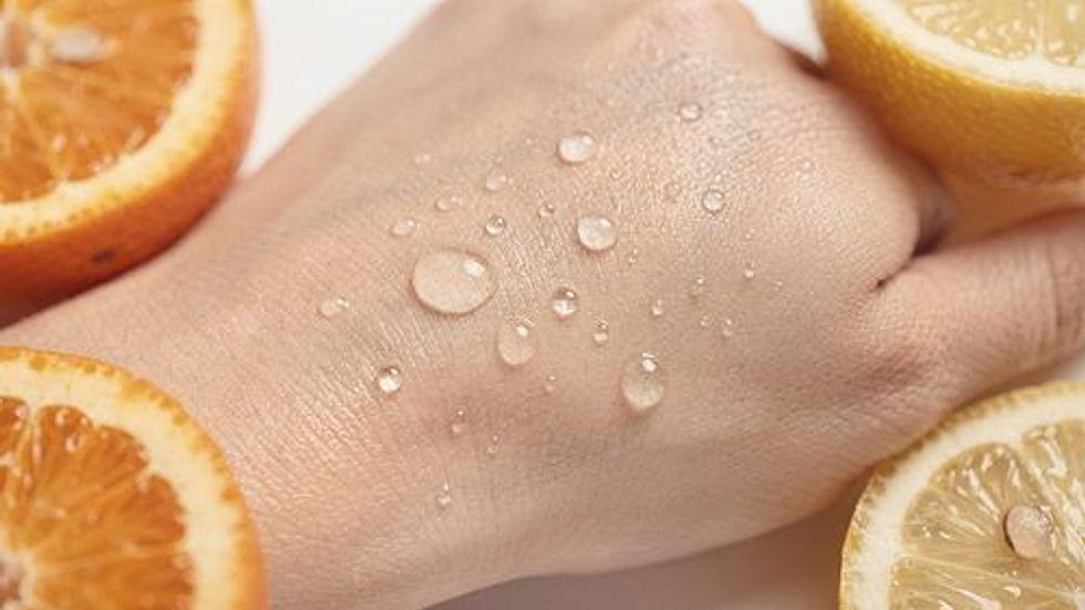 Water droplets on a hand surrounded by orange and lemon halves, against a light background. The scene suggests freshness and vitality.