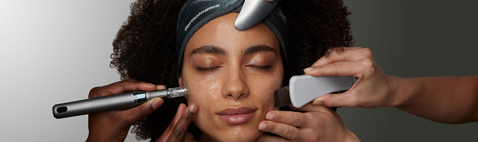 Woman receiving facial treatment with various skincare tools. She wears a headband labeled "dermalogica." Background is gray.
