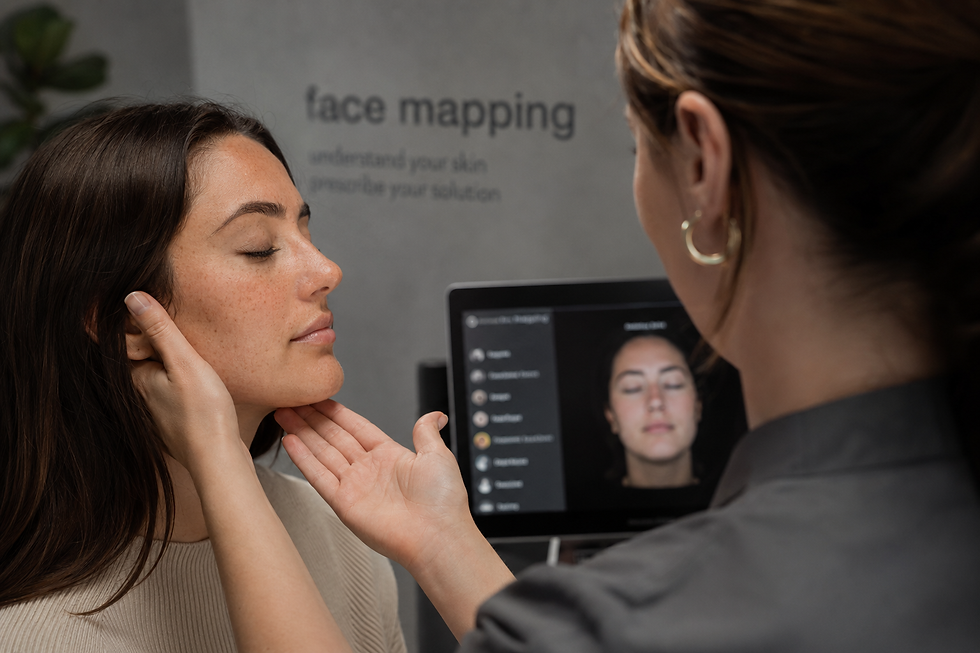 A woman with closed eyes receives a facial assessment. A screen displays her face with text "face mapping" in the background.