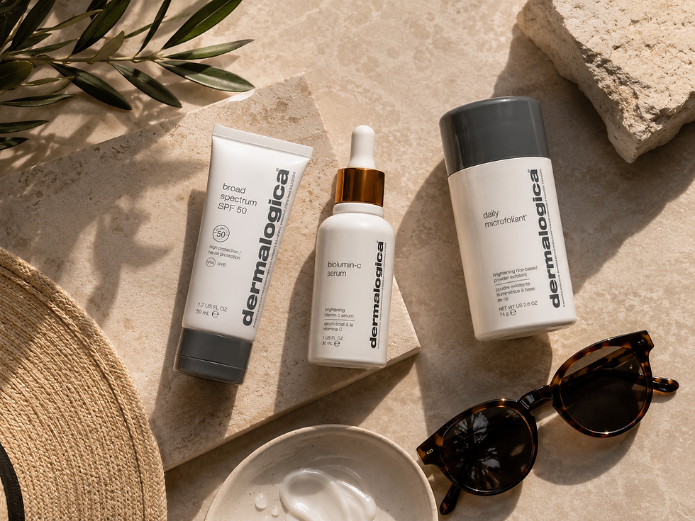 Sunlit flat lay of Dermalogica SPF, serum and microfoliant beside sunglasses, straw hat and cream tiles on beige stone.