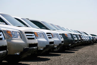 Row of modern SUVs in a lot, classic vehicles for sale.