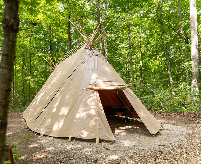 A traditional tipi set up in the forest.