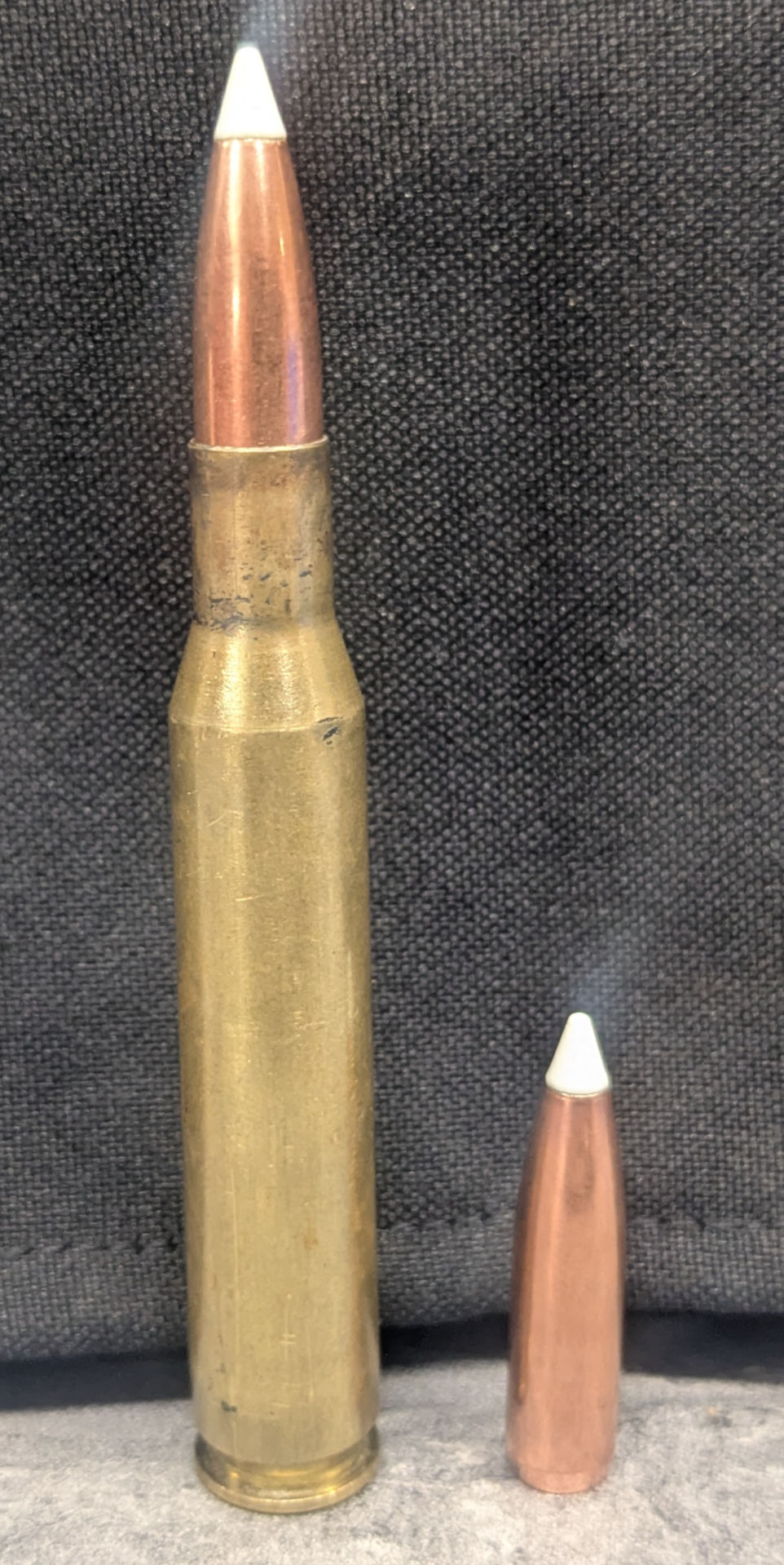 Loaded .270 Winchester cartridge with a 130gr Nosler AccuBond bullet seated in Hornady brass, shown beside a separate bare AccuBond bullet on a gray background.