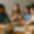 Vier studenten zitten geconcentreerd rond een tafel met laptops, boeken en notitieblokken. Eén student legt iets uit, terwijl de anderen aandachtig luisteren en aantekeningen maken — een realistische setting waarin samenwerking, analyse en waardegericht leiderschap centraal staan.
