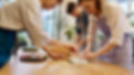 Three people making sushi at a table with focus and attention to detail.