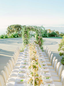 Overgrown wedding floral arch made of garden roses, ranunculus, and airy foliage in soft green and ivory tones, set against the mountain backdrop at Stone Mountain Estate in Malibu, CA.