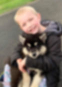 Young boy smiling while hugging a black and tan puppy