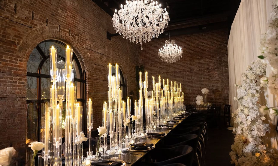 Elegant table setting with candles and chandeliers in a dimly lit room.