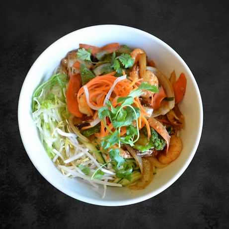 Bowl of noodles with vegetables, garnished. 