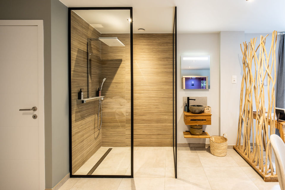 Spa privatif Charleroi L’Annexe Douceur douche moderne avec paroi vitrée et salle de bain naturelle espace Misty