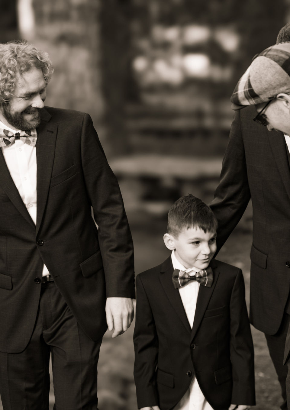 Men in suits and boy walking through wooded area wearing bowties.