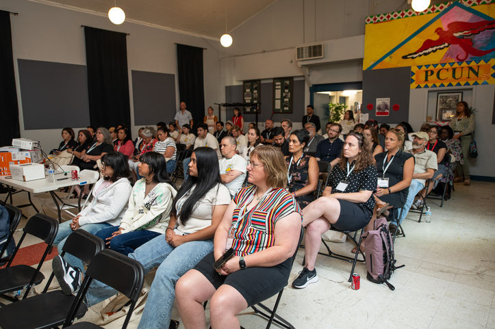 Audience at event in room. PCUN banner on wall. People listening intently. Oregon Worker Relief Summit.