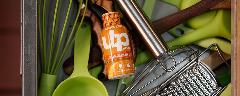 Commercial product photography featuring UpShot Energy Refreshers surrounded by kitchen utensils for a branded advertising campaign.