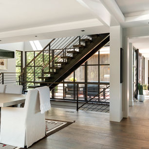Modern steel staircase with open risers inside contemporary ranch style luxury home.