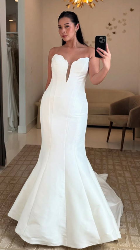 Bride to be wearing clean wedding dress with Mermaid silhouette in ivory Mikado with scalloped edging cat-eye neckline.