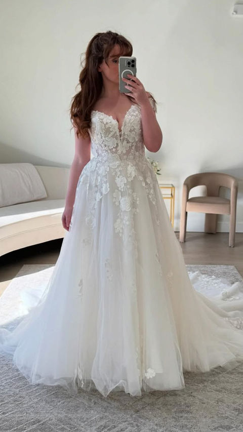 Woman taking a picture on the mirror wearing an Eddy K ballgown with ivory lace over champagne tulle, 3D appliqués