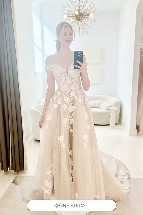 Woman taking a picture on the mirror wearing an Eddy K ballgown with ivory lace over champagne tulle, 3D appliqués