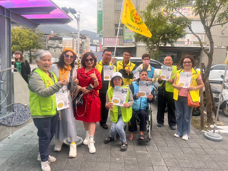 宜蘭縣肢體障礙者協會志工小組在路旁向民眾介紹第十六屆公益票選活動，手持宣傳單與旗幟，展現社區動員的溫暖力量。