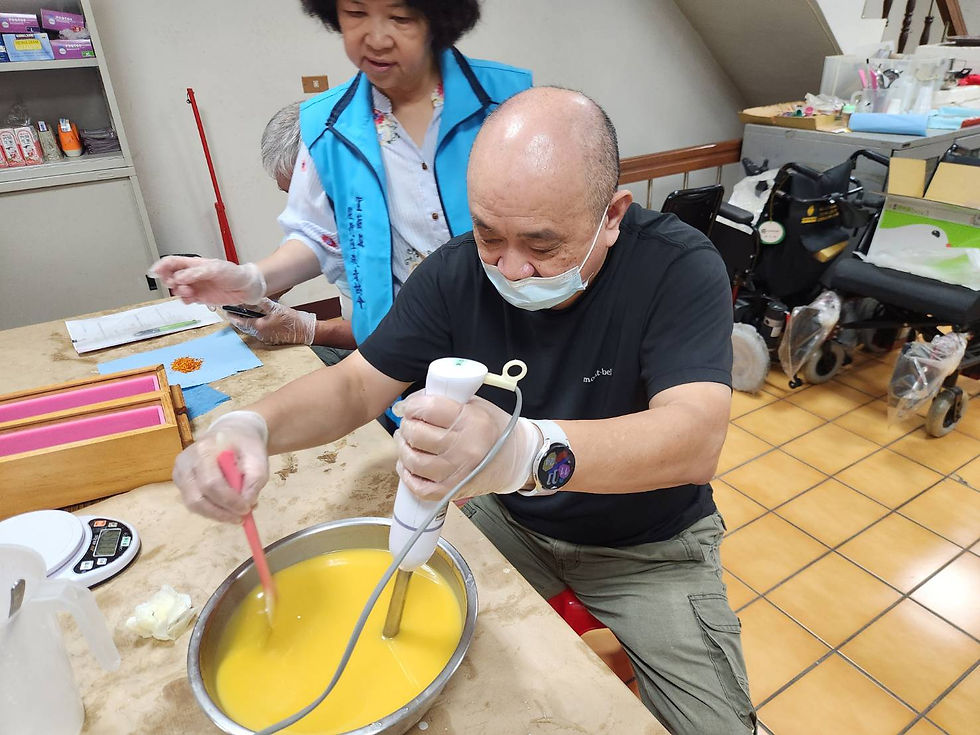 男性學員在旁人協助下,穩健地握持攪拌器進行實作,體驗手工皂製作樂趣。
