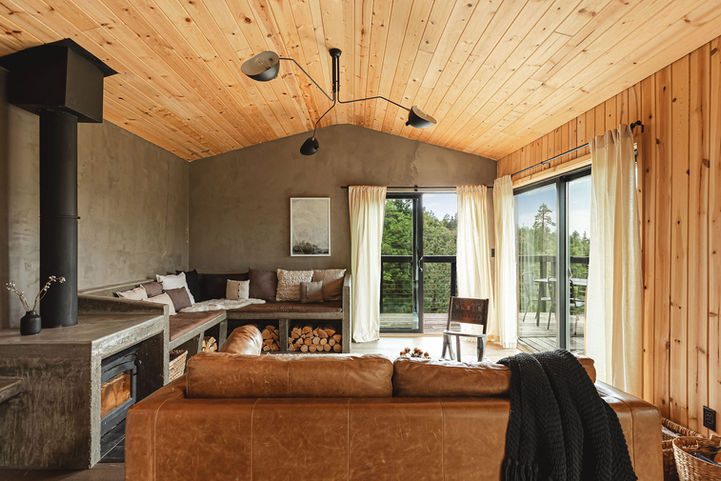 Bear Mountain Chalet, designed by Studio Lins. Photography by Gianna Christina Photo. Image shows a modern living room with cement-colored plaster walls and view of pine trees. 