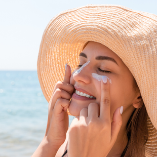 woman wearing sunscreen on face with a hat on